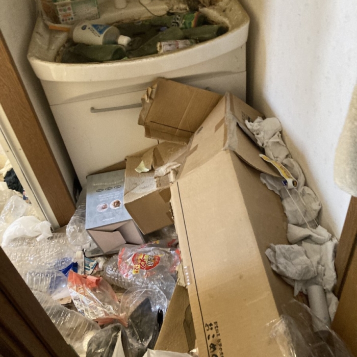 ゴミで溢れた洗面所｜大量の段ボールやペットボトルが散乱し、洗面台は使用不可能な状態