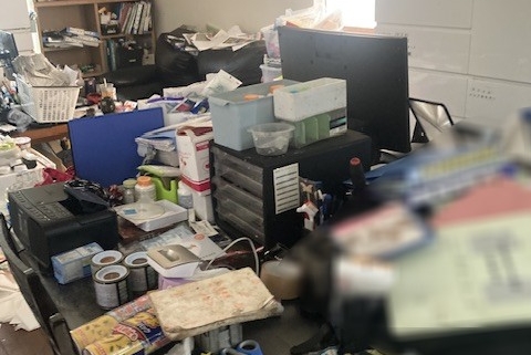 作業前のダイニング・キッチン｜書類や調味料、ゴミが机全体に散乱し、床も見えないほど物で覆われた状態