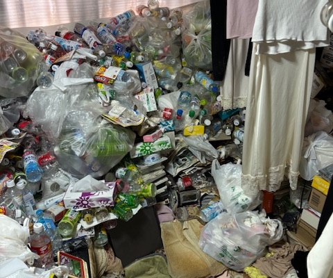 ゴミ屋敷の片付け前｜1DKの居室に天井近くまで積み上がったペットボトルや食品ごみ、雑誌や衣類などが散乱している状態